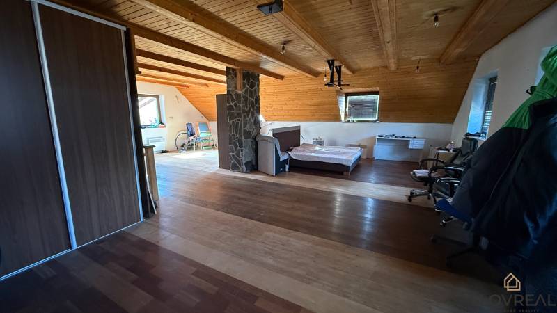 Moderný 5-izbový rodinný dom po kolaudácii 2025 | 2-generačné bývanie  - Podkrovná izba s posteľou, skriňou a podlahou s dreveným dekorom v rodinnom dome.