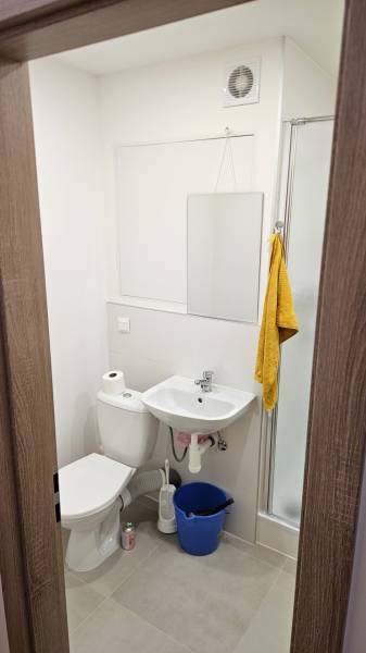 Prenájom garsónka Dubnica nad Váhom  - Kúpeľňa v garsónke s umývadlom, toaletou, sprchou a zrkadlom, neutrálne farby.