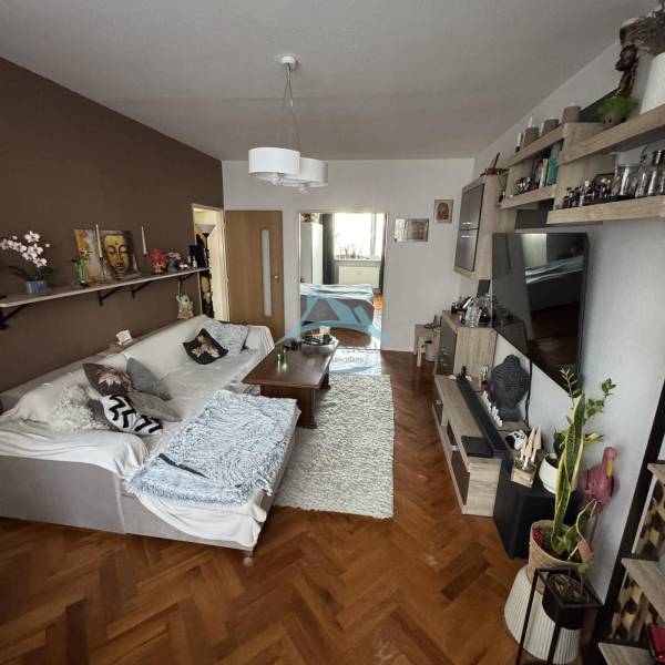 PREDAJ: 3-izbový byt 77 m², Šahy – Výborná investícia aj bývanie  - Obývačka so sedačkou, stolom a podlahou s dreveným dekorom v 3-izbovom byte.