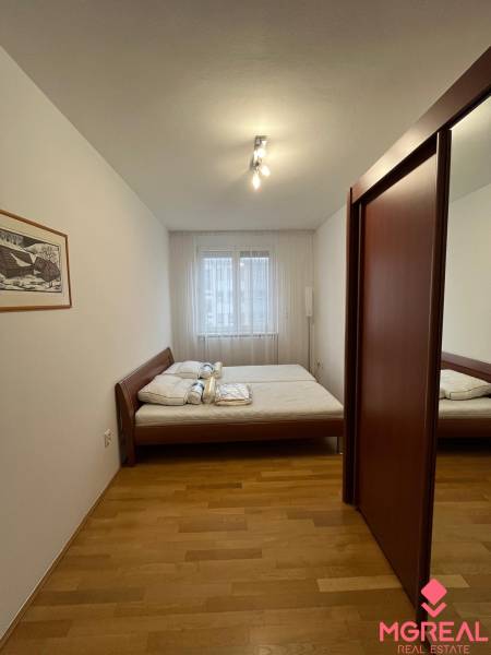 3i byt za cenu 2i bytu, Staré Mesto - Spálňa s posteľou, vstavanou skriňou a podlahou s dreveným dekorom v 3-izbovom byte.