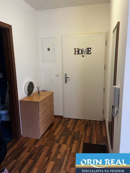 ÚTULNÝ 2 IZBOVÝ BYT - SILVANIUM  - Vstupná chodba v 2-izbovom byte s drevenou podlahou a komodou.