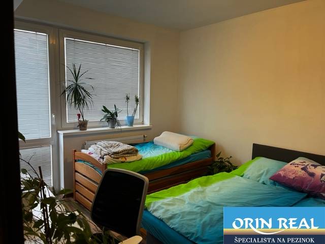 ÚTULNÝ 2 IZBOVÝ BYT - SILVANIUM  - Spálňa v 2-izbovom byte s dvomi jednolôžkami, stolom a izbovými rastlinami.