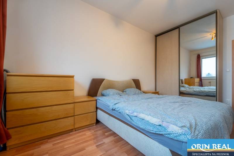 SVETLÝ ZARIADENÝ 2-IZBOVÝ BYT S BALKÓNOM - LA VITA  - Spálňa v 2-izbovom byte so zrkadlovou skriňou a posteľou, podlaha s dreveným dekorom.