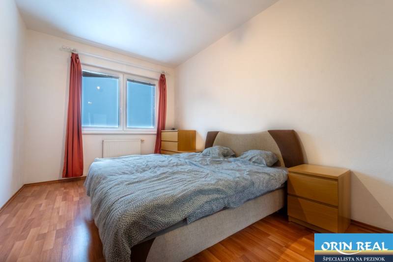 SVETLÝ ZARIADENÝ 2-IZBOVÝ BYT S BALKÓNOM - LA VITA  - Spálňa v 2-izbovom byte s posteľou, prírodnými farbami a podlahou s dreveným dekorom.