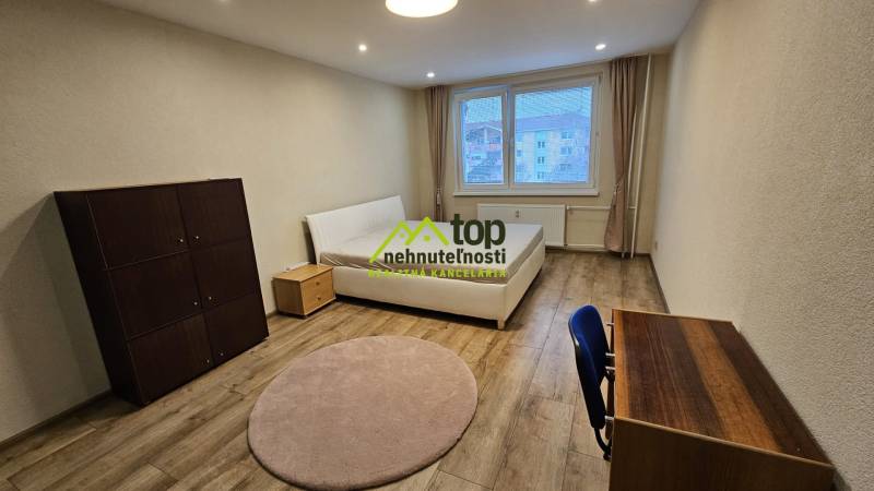 Prenájom 2 izbový byt v Topoľčanoch, sídlisko JUH - Svetlá izba v 2-izbovom byte s posteľou a nábytkom, podlaha s dreveným dekorom.