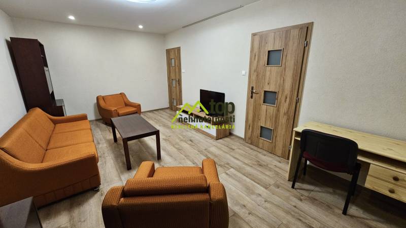 Prenájom 2 izbový byt v Topoľčanoch, sídlisko JUH - Obývacia izba v 2-izbovom byte s oranžovým nábytkom a podlahou s dreveným dekorom.