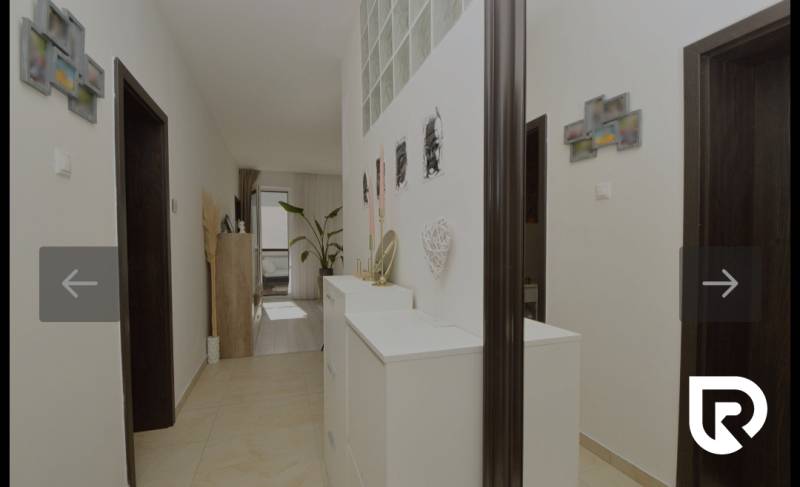 RADO I 4-IZBOVY murovaný ROD.DOM I RAJKA - Chodba v rodinnom dome s bielymi skriňami, dekoráciami a rastlinou.