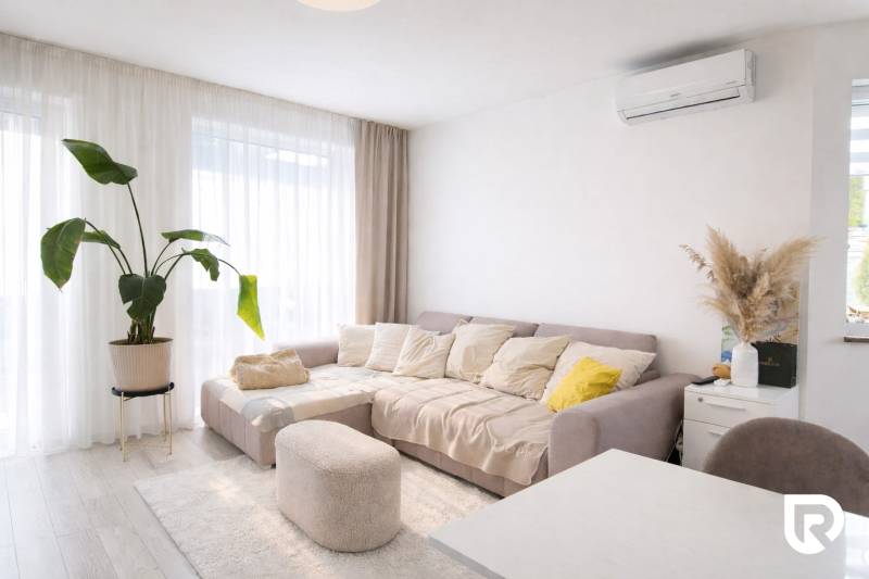 RADO I 4-IZBOVY murovaný ROD.DOM I RAJKA - Obývacia izba rodinného domu so svetlou sedačkou, rastlinou a podlahou s dreveným dekorom.