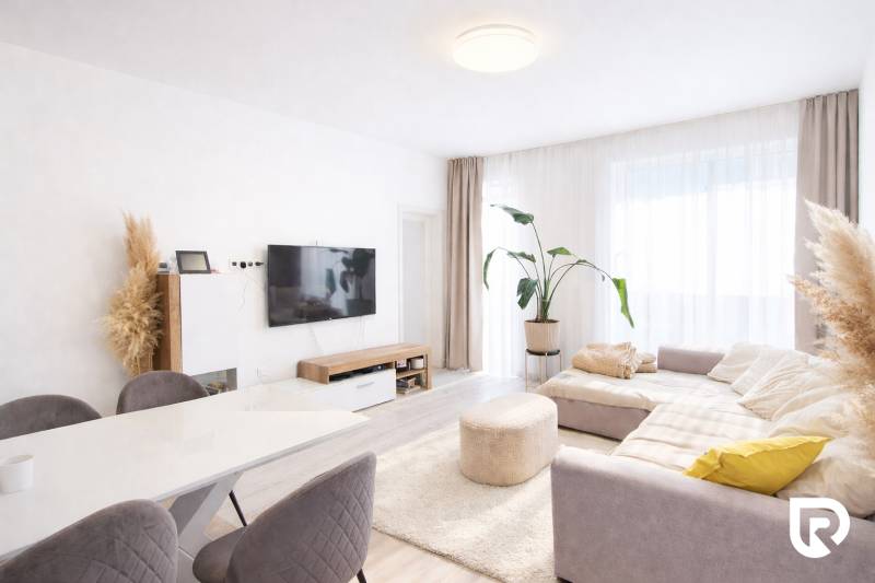 RADO I 4-IZBOVY murovaný ROD.DOM I RAJKA - Svetlá obývačka s televízorom, rohovým gaučom, kvetom a stolom v rodinnom dome.