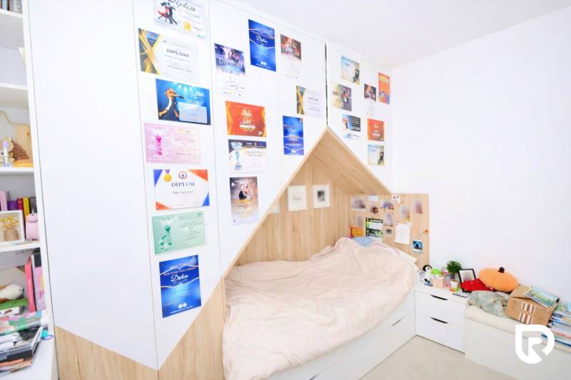 RADO I 4-IZBOVY murovaný ROD.DOM I RAJKA - Spálňa v rodinnom dome s posteľou, diplomami na stene a bielym nábytkom.