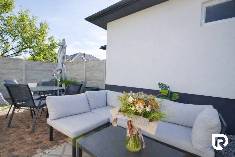 RADO I 4-IZBOVY murovaný ROD.DOM I RAJKA - Rodinný dom v Rajke s terasou, pohodlným sedením a stolom, kvetinová dekorácia.