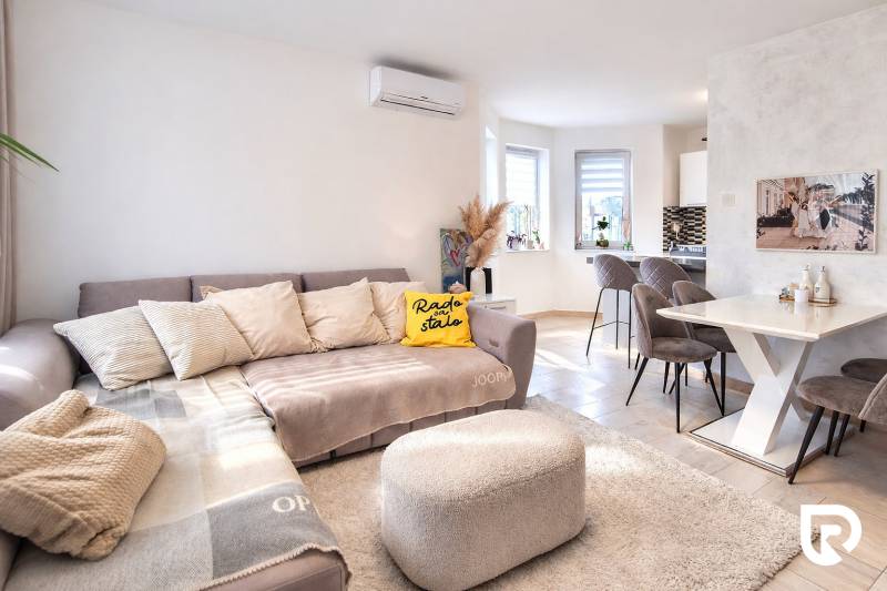 RADO I 4-IZBOVY murovaný ROD.DOM I RAJKA - Obývacia izba v rodinnom dome s pohovkou, jedálenským stolom a podlahou s dreveným dekorom.