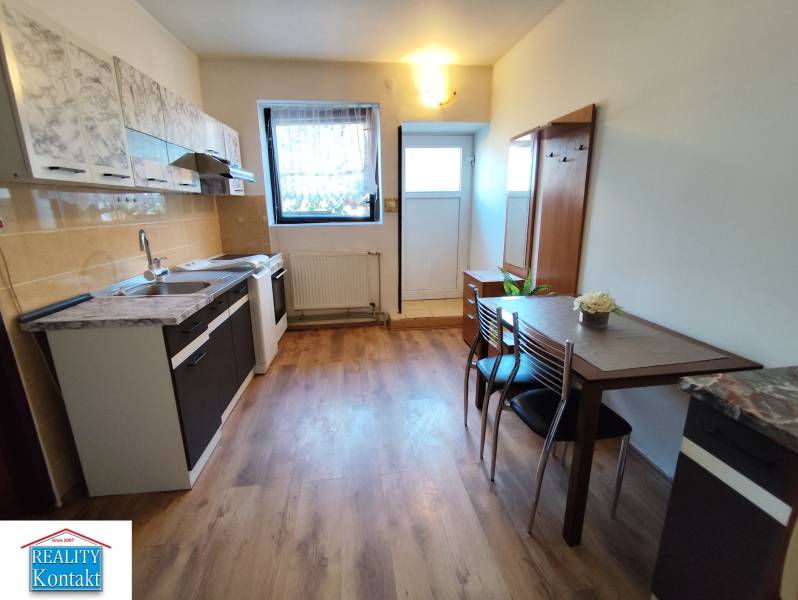 Na prenájom 1-izbový byt - Nové Zámky - Kuchyňa v 1-izbovom byte s podlahou s dreveným dekorom a jedálenským stolom.