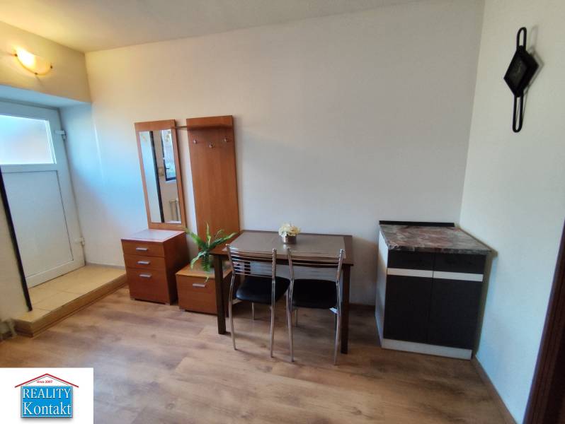 Na prenájom 1-izbový byt - Nové Zámky - Interiér 1-izbového bytu s nábytkom a podlahou s dreveným dekorom.