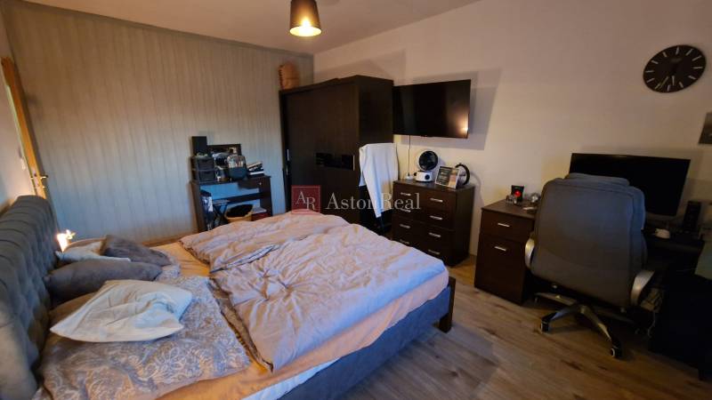 EXKLUZÍVNE-PREDAJ 3-IZBOVÝ BYT POPRAD, juh-bl.Slnečnica 80 m2  2 balk. - Spálňa v 3-izbovom byte s komfortnou posteľou, pracovným stolom a podlahou s dreveným dekorom.