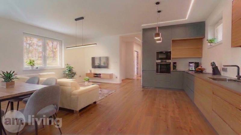 NOVINKA - 2x Novostavba RODINNÝCH DOMOV - Borčice  - Obývacia izba v rodinnom dome so sedačkou a podlahou s dreveným dekorom.