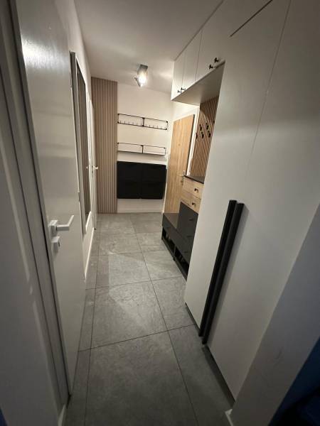 Na predaj moderný 2-izbový byt po kompletnej rekonštrukcii – Piešťany - Chodba v 2-izbovom byte s dlažbou, skrinkami a drevenými stenovými panelmi.