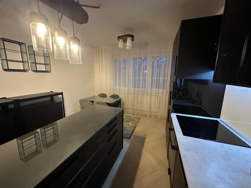 Na predaj moderný 2-izbový byt po kompletnej rekonštrukcii – Piešťany - Kuchyňa v 2-izbovom byte so sklenenými svietidlami a podlahou s dreveným dekorom.