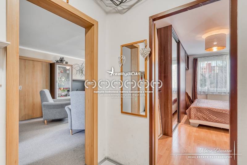 REZERVOVANÉ 4-izbový byt v Trnave na Veternej ulici - Interiér 4-izbového bytu s podlahou s dreveným dekorom, nábytkom a zrkadlom.