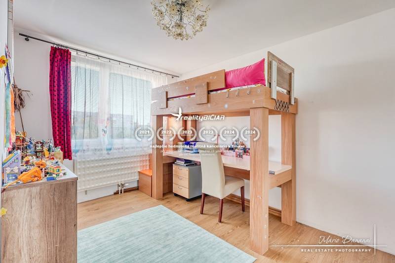 REZERVOVANÉ 4-izbový byt v Trnave na Veternej ulici - Detská izba so zvýšenou posteľou, podlahou s dreveným dekorom a hračkami na policiach.