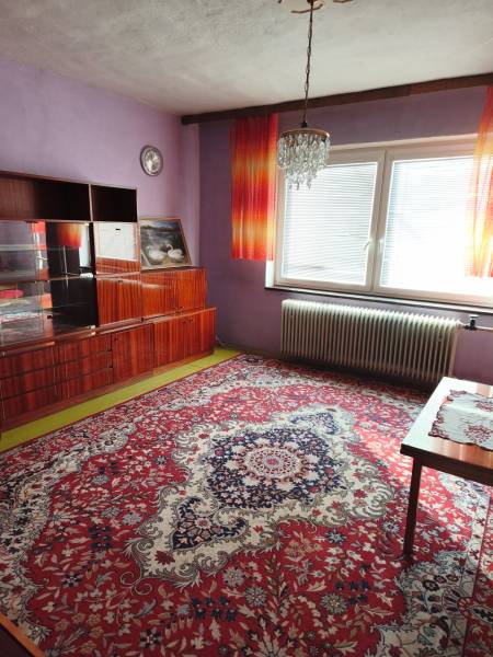 5 izbový dom Mankovce - Fialové steny a luxusný luster zdobia miestnosť v rodinnom dome s výrazným kobercom.