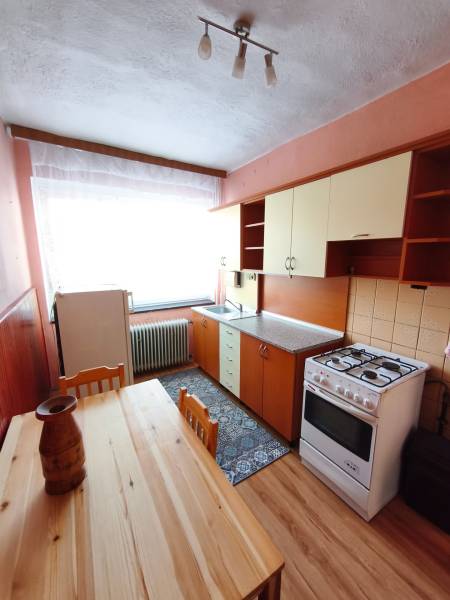 5 izbový dom Mankovce - Kuchyňa v rodinnom dome s dreveným dekorom podlahy, plynový sporák, jedálenský stôl.