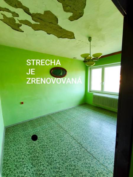 5 izbový dom Mankovce - Izba v rodinnom dome s opadanou omietkou a zelenými stenami.