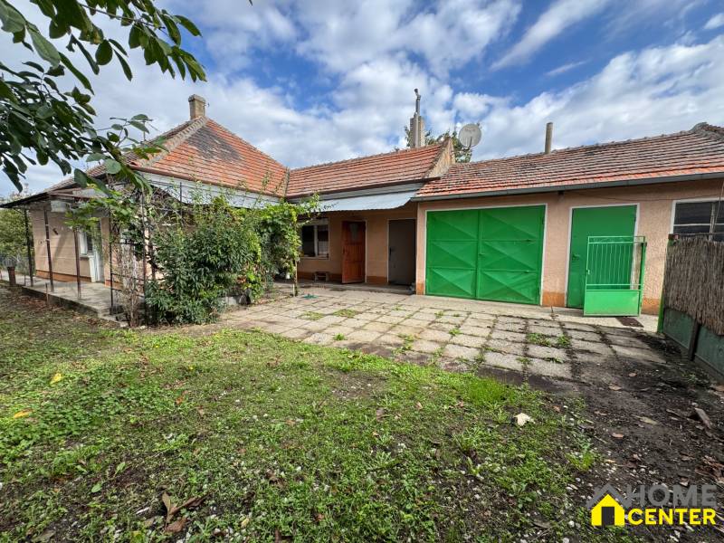 NA PREDAJ!!! Rodinný dom s veľkým pozemkom v obci Vék pri Hurbanove - Záhrada a terasa pri rodinnom dome v Komárne s garážovými dverami a záhradným porastom.