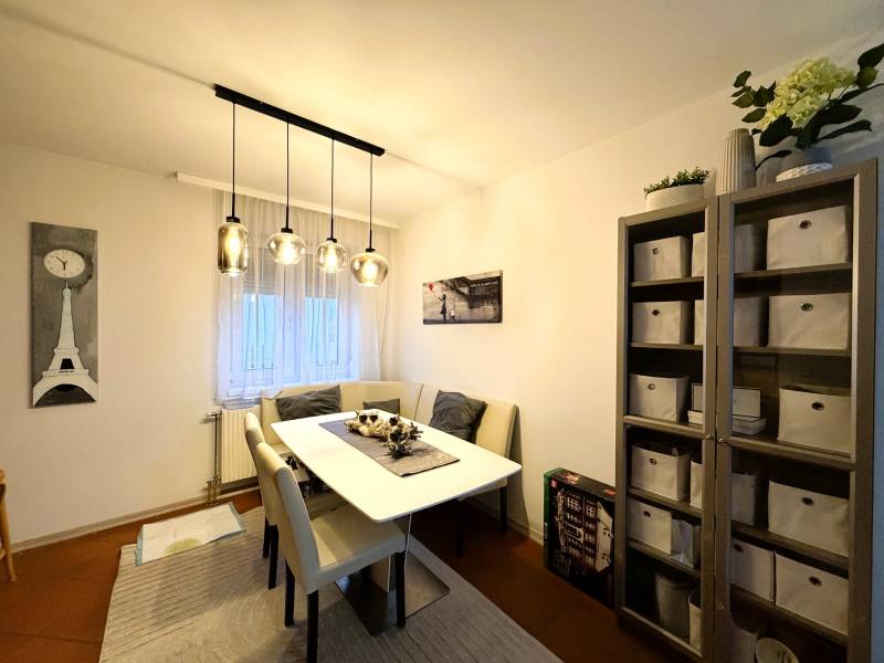 3 izbový byt s balkónom v obľúbenej lokalite Neusiedl am See - Jedáleň so stolom, stoličkami a regálom v 3-izbovom byte s dekoratívnym osvetlením.