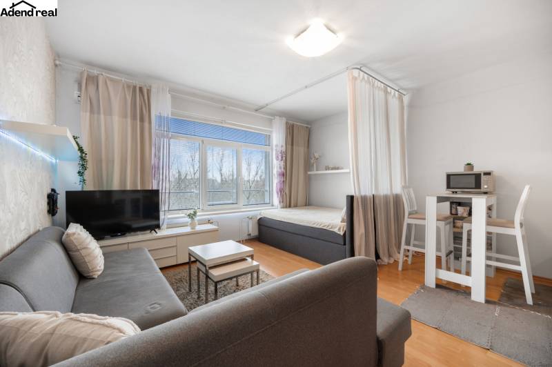 Na predaj príjemný zariadený 1 izbový byt na ulici Antolská, Petržalka - Obývacia časť 1-izbového bytu s pohovkou, TV, jedálenským stolom a posteľou.