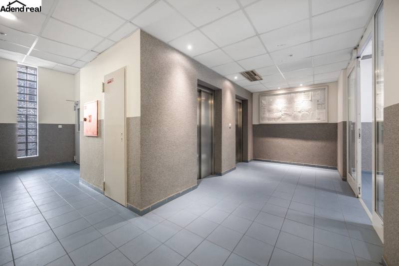 Na predaj príjemný zariadený 1 izbový byt na ulici Antolská, Petržalka - Vstupná hala s výťahmi, modrá podlaha, osvetlené stropy.