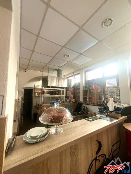 PRENÁJOM - Bistro/ Gastro prevádzka - Košice - Juh - Interiér gastro priestoru s podlahou s dreveným dekorom, pultom, zákuskom a taniermi.