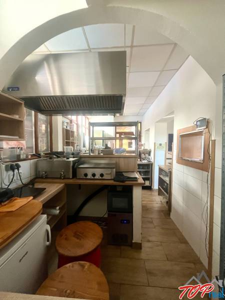 PRENÁJOM - Bistro/ Gastro prevádzka - Košice - Juh - Kuchynský priestor s nerezovým digestorom a podlahou s dreveným dekorom v gastro priestoroch.