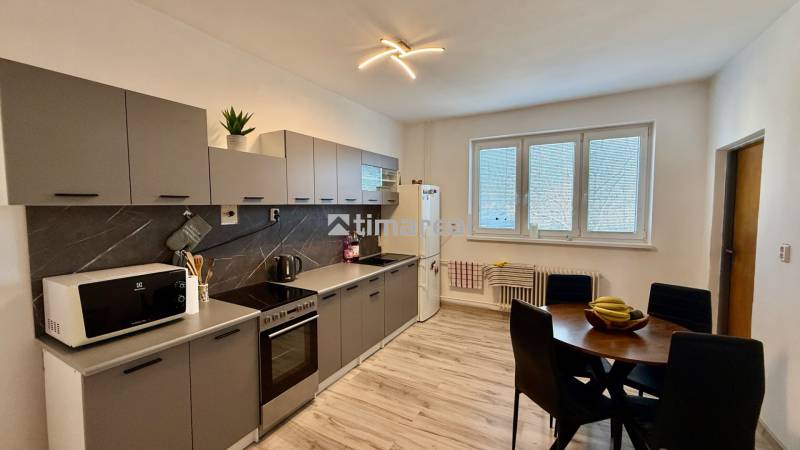 * 7i rodinný dom, veľký 33.5á pozemok, Brestovany - Kuchyňa s podlahou s dreveným dekorom, sivými skrinkami a jedálenským stolom v Rodinnom dome.