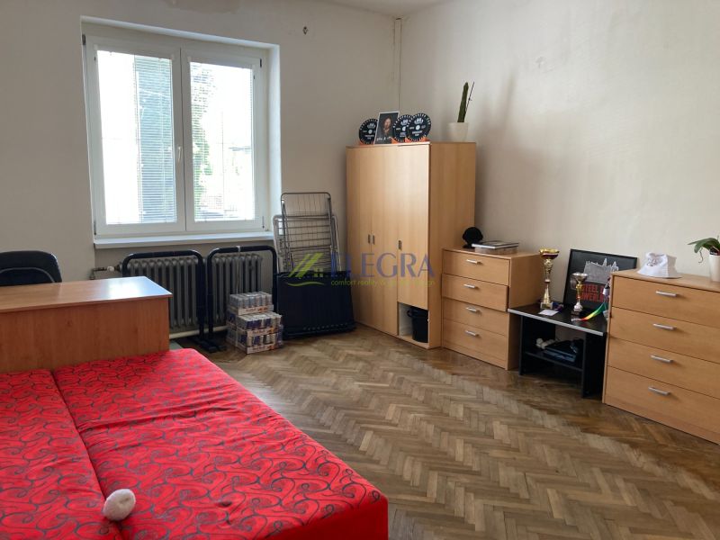 Na predaj  rodinný dom ulica Mudroňova Košice - Interiér rodinného domu s podlahou s dreveným dekorom, červenou posteľou a skriňami.
