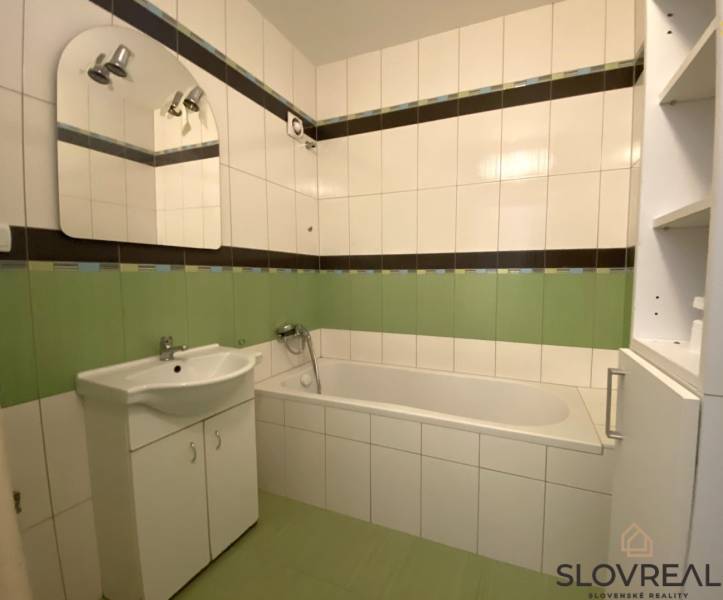 Predaj 3 - izbového bytu - Nová Baňa - Kúpeľňa v 3-izbovom byte s vaňou, umývadlom a zelenými obkladmi.