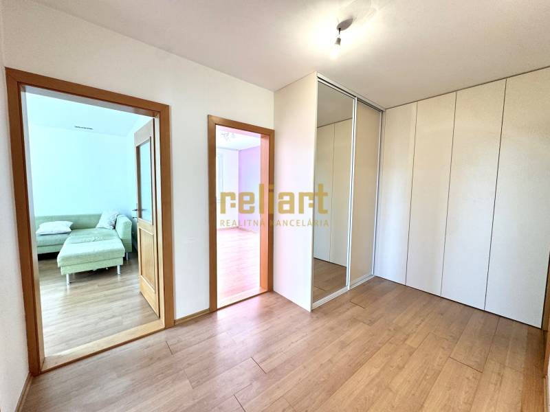 Zrekonštruovaný 3i byt na začiatku Petržalky, električka, les, výhľady - Interiérová fotografia 3-izbového bytu s podlahou v drevenom dekore a vstavanou skriňou.