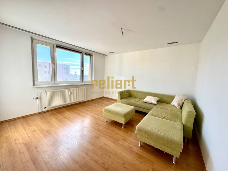 Zrekonštruovaný 3i byt na začiatku Petržalky, električka, les, výhľady - Obývacia izba v 3-izbovom byte s podlahou s dreveným dekorom a zelenou sedačkou.