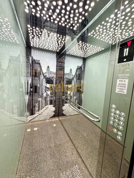 Zrekonštruovaný 3i byt na začiatku Petržalky, električka, les, výhľady - Interiér výťahu s čiernobielymi stenami v budove s 3-izbovými bytmi.