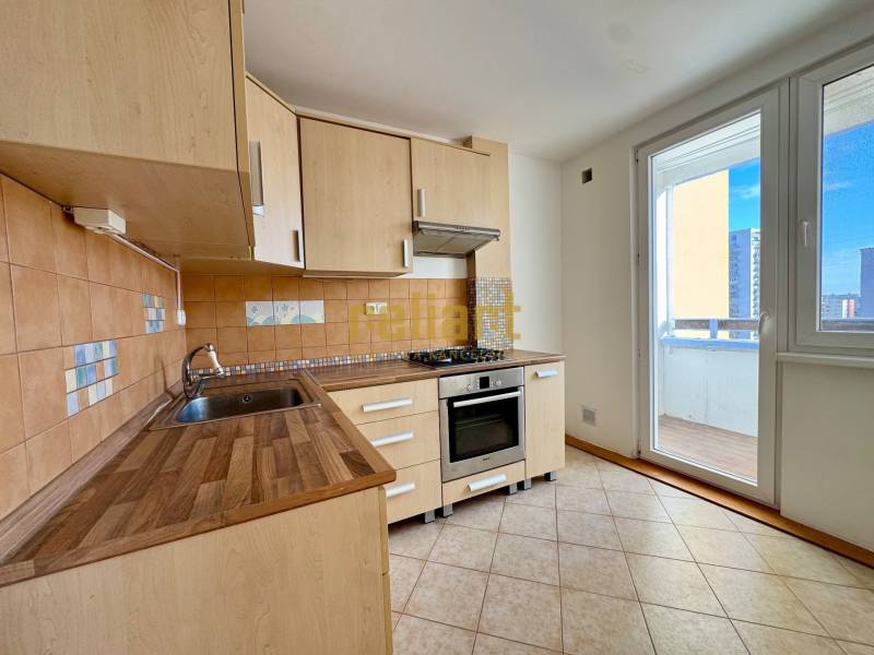 Zrekonštruovaný 3i byt na začiatku Petržalky, električka, les, výhľady - Kuchyňa v 3-izbovom byte s podlahou s dreveným dekorom a východom na balkón.