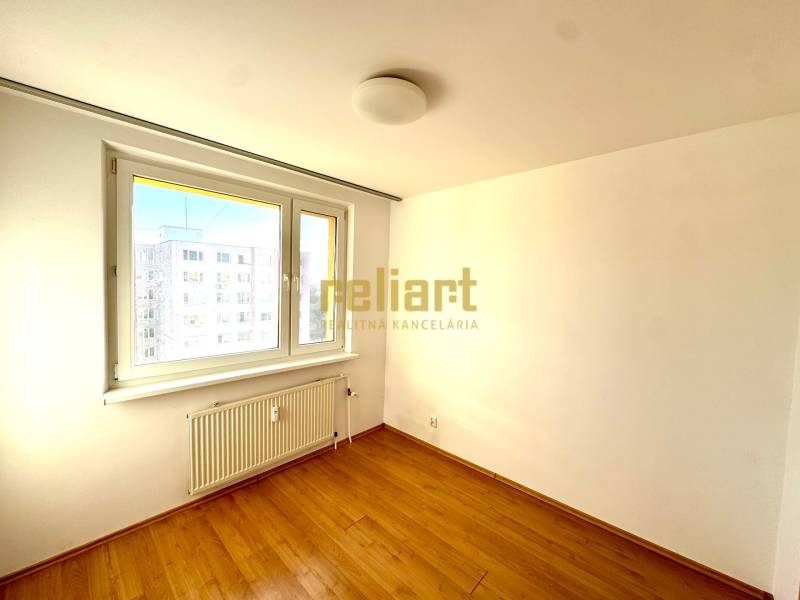 Zrekonštruovaný 3i byt na začiatku Petržalky, električka, les, výhľady - Izba v 3-izbovom byte s bielymi stenami a podlahou s dreveným dekorom.