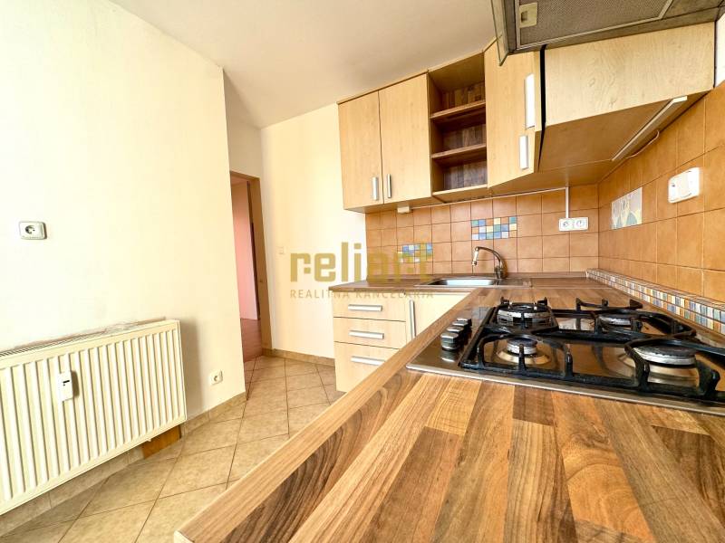 Zrekonštruovaný 3i byt na začiatku Petržalky, električka, les, výhľady - Kuchyňa s podlahou s dreveným dekorom a plynovým sporákom v 3-izbovom byte.