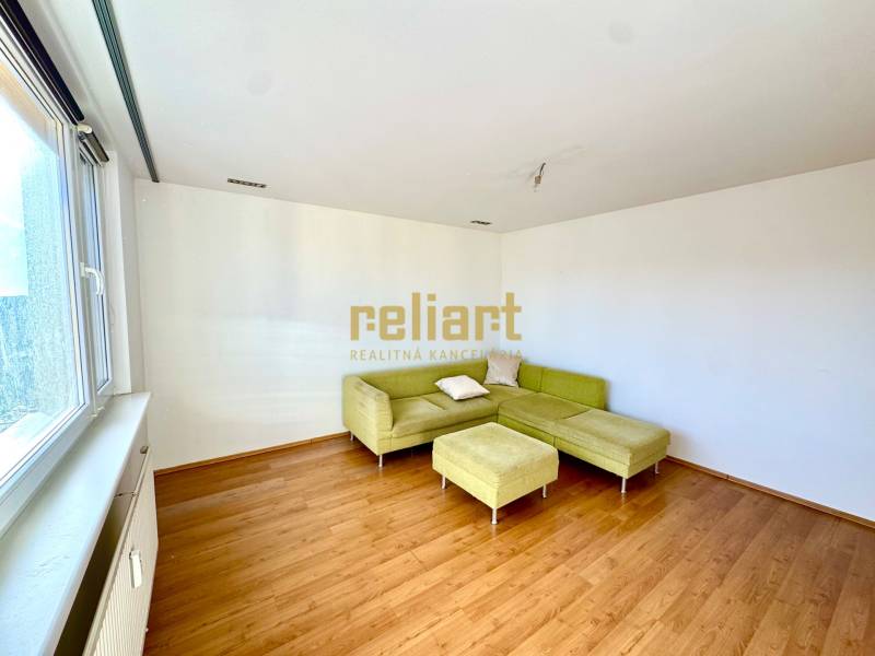 Zrekonštruovaný 3i byt na začiatku Petržalky, električka, les, výhľady - Obývacia izba s rohovou sedačkou a podlahou s dreveným dekorom v 3-izbovom byte.