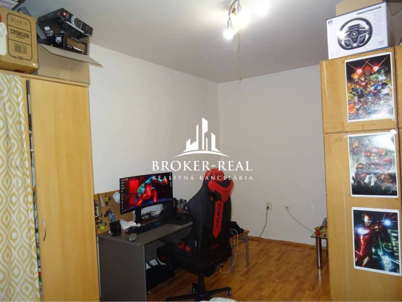 1 - izbový byt Košice, Popradská - Izba v 1-izbovom byte s počítačom, kreslom a podlahou s dreveným dekorom.