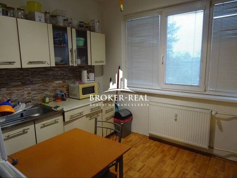 1 - izbový byt Košice, Popradská - Kuchyňa v 1-izbovom byte s podlahou s dreveným dekorom a jedálenským stolom.