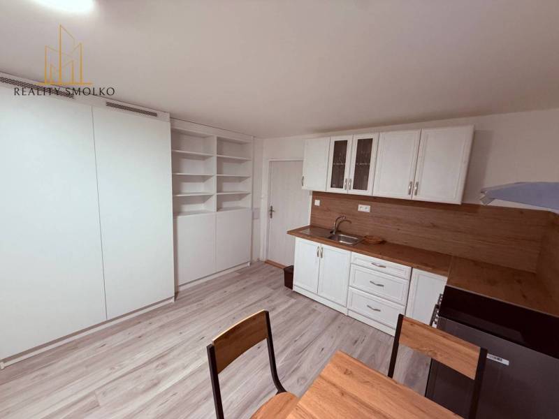 EXKLUZÍVNE: Štýlové bývanie v tichej lokalite Kanaša – po kompletnej r - Kuchyňa v rodinnom dome s bielou linkou, vstavanými poličkami a podlahou s dreveným dekorom.