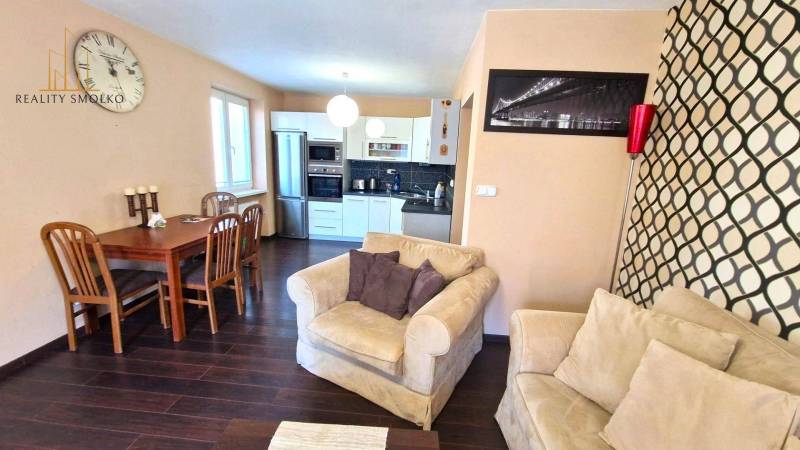 PRENÁJOM 2i, 56 m², PREŠOV- KOMENSKÉHO - Obývačka v 2-izbovom byte s kuchyňou, sedačkou a podlahou s dreveným dekorom.