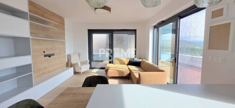 LUXUSNÝ 3i byt,PARKING,CHLADENIE,TERASA,Grand Koliba, Frankovská ulica - Obývačka v 3-izbovom byte s gaučom, kreslom, vstavanou skriňou a priamym výhľadom na terasu.