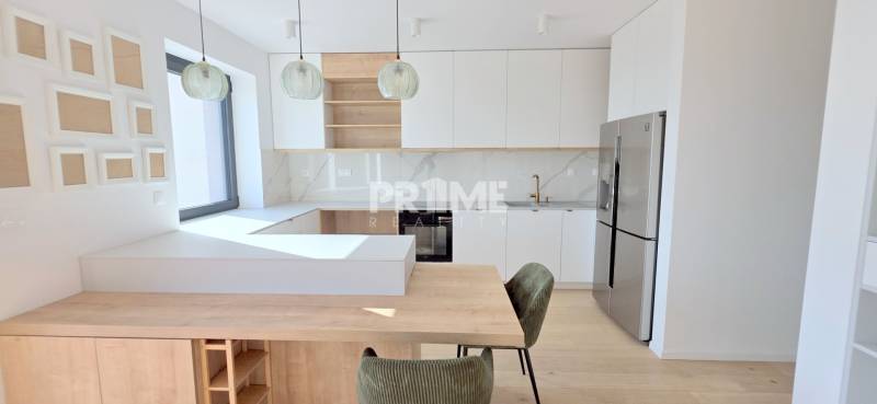 LUXUSNÝ 3i byt,PARKING,CHLADENIE,TERASA,Grand Koliba, Frankovská ulica - Kuchyňa v 3-izbovom byte s drevenými a bielymi prvkami a závesnými lampami.