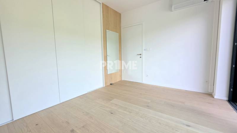 LUXUSNÝ 3i byt,PARKING,CHLADENIE,TERASA,Grand Koliba, Frankovská ulica - Izba v 3-izbovom byte s drevenou podlahou, vstavanou skriňou a bielymi stenami.